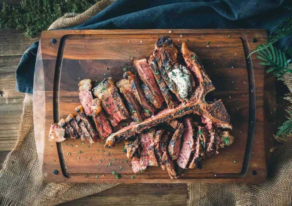 Sliced t-bone steak on cutting board.