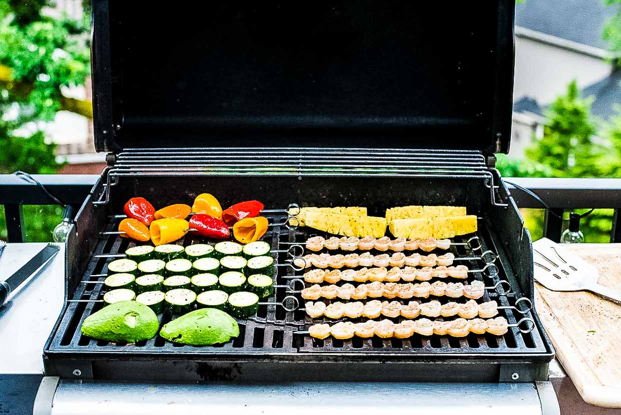 Skewers of shrimp, pineapple, peppers, zucchini and avocado on the grill. 