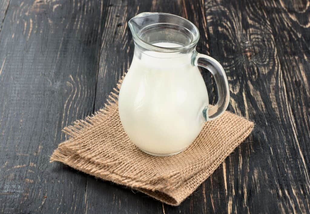 Heavy cream in glass jug with wooden background.