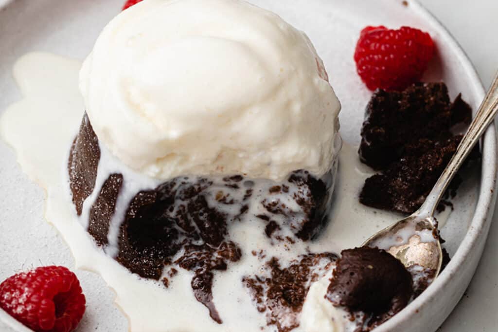 An Instant Pot lava cake on a plate with ice cream and raspberries.