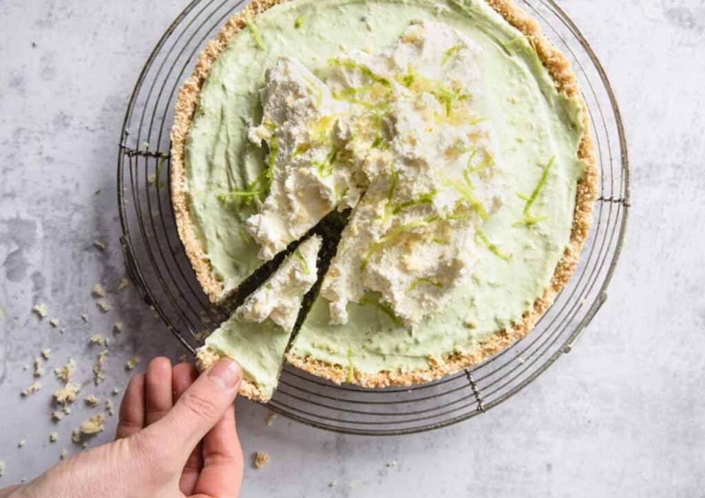A hand pulling out a slice of keto key lime pie.