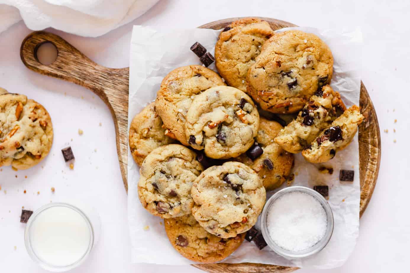 Chocolate chip cookies sit on a plate next to a glass of refreshing milk.