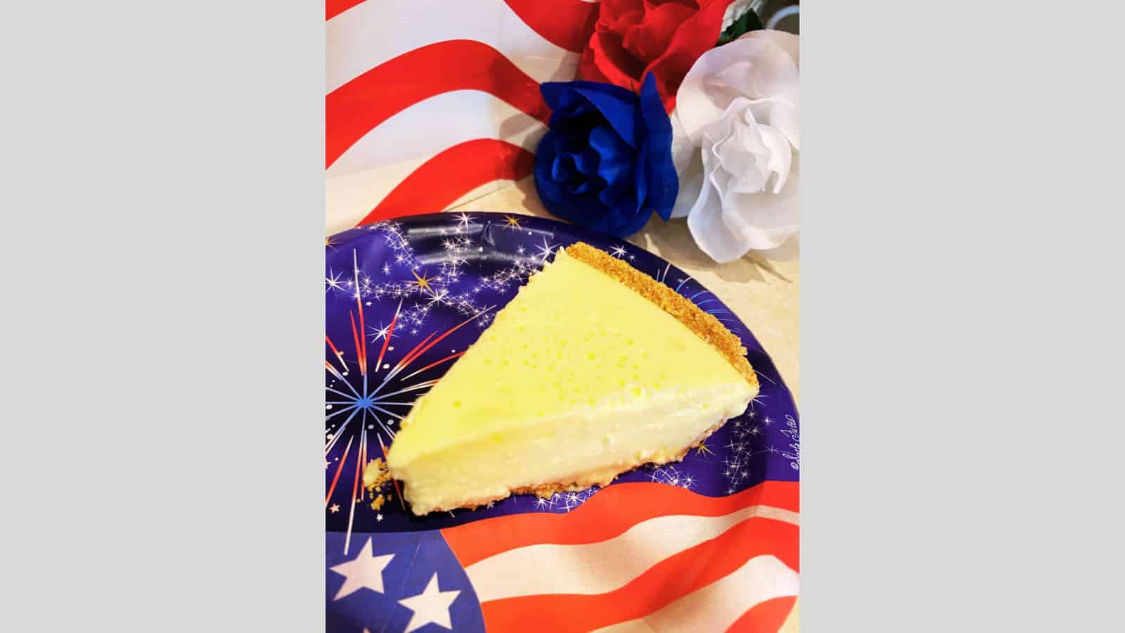 Slice of lemon cheesecake on red, white, and blue plate.