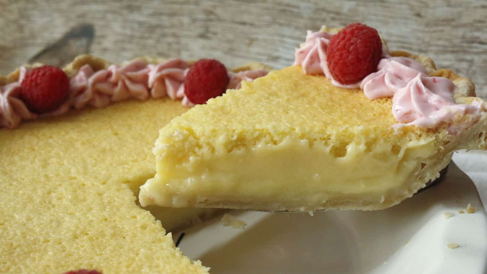 A slice of lemon pie with raspberries on top.