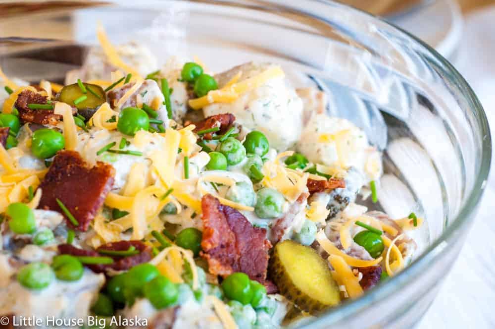 Close up shot of Loaded Potato Salad with chunks of bacon, cheese, pickles, anc cheese.