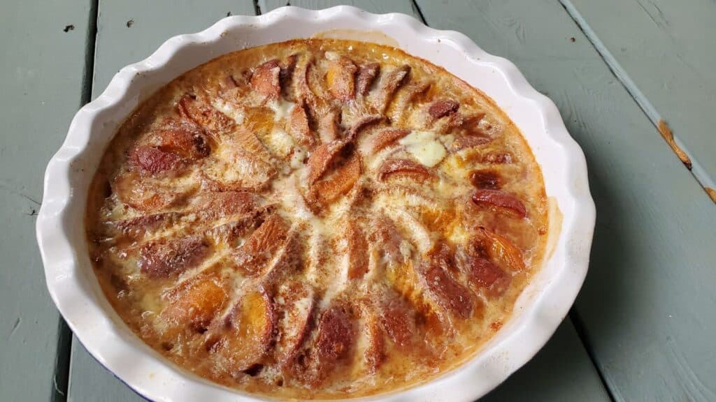 Low angle shot of a peach kuchen in a ceramic pie pan.