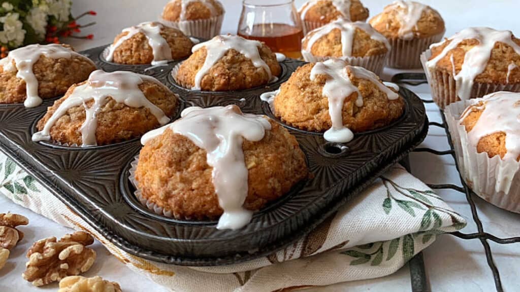 Muffins in a pan with icing and walnuts.