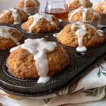 Muffins in a pan with icing and walnuts.