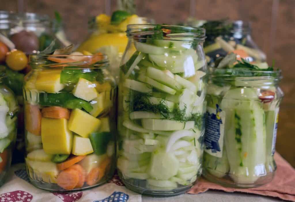 Mason jars of fermenting squash and cucumbers.