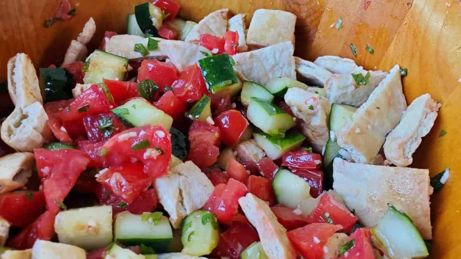 Image shows a Mediterranean Cucumber Tomato Salad in a wooden bowl closeup.