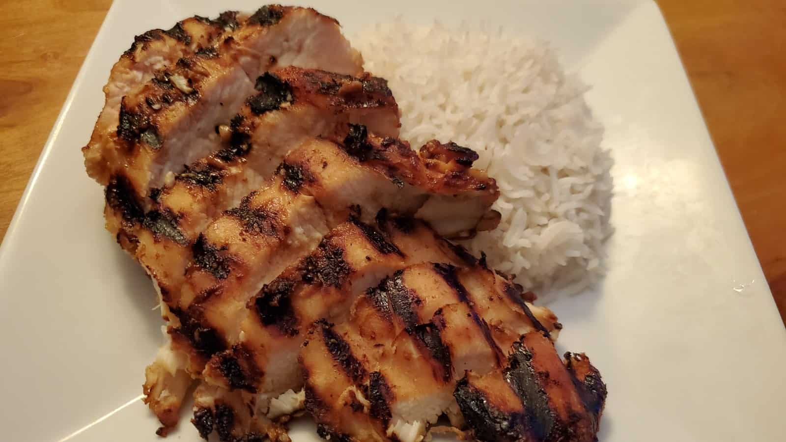 Miso glazed chicken with rice on a white plate.