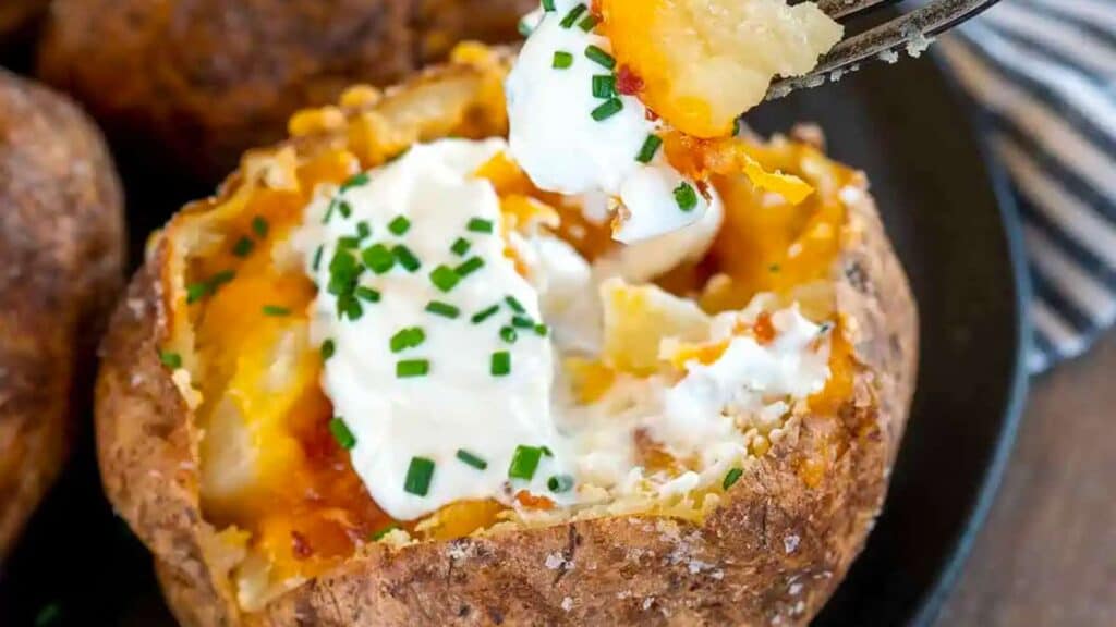 Fork digging into loaded potato.