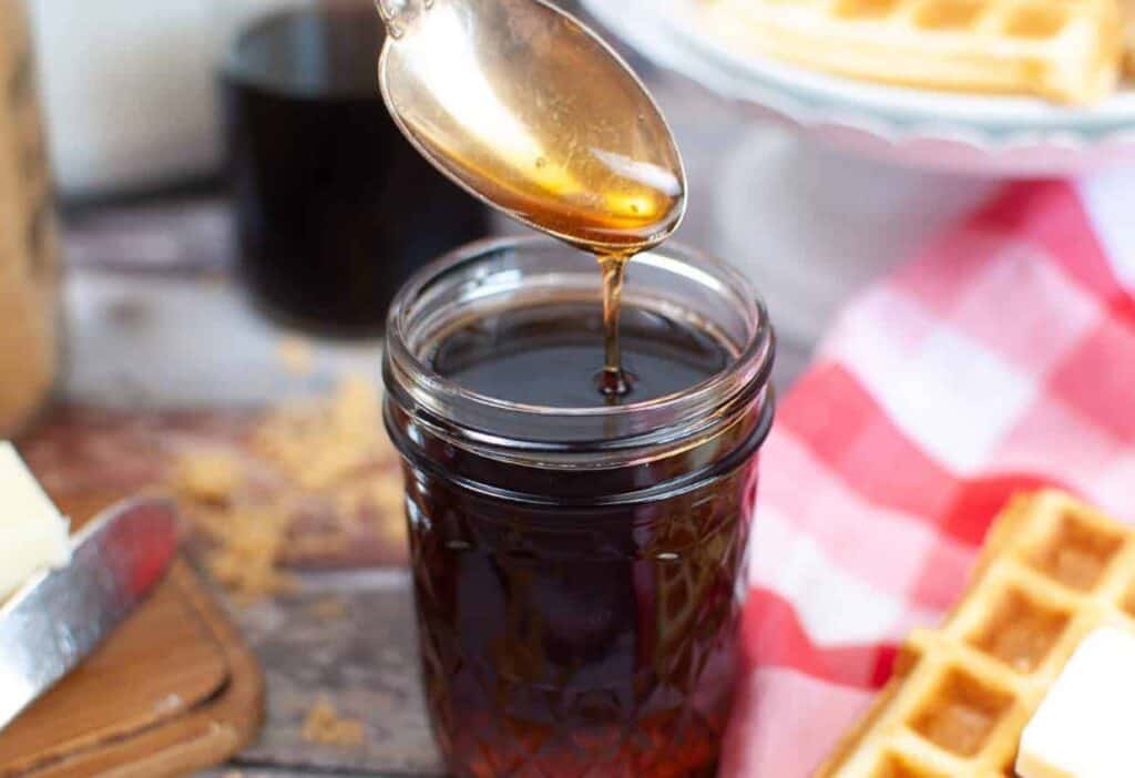 Homemade pancake syrup on spoon and in mason jar.