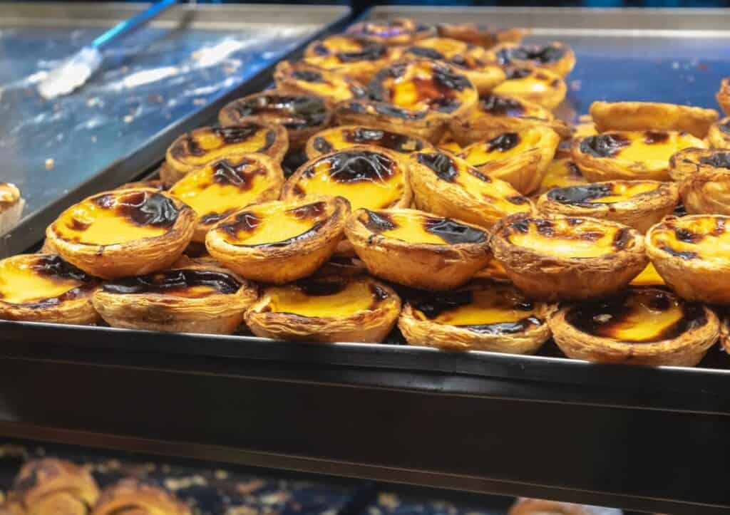 Pile of freshly baked pastel de natas on a tray.