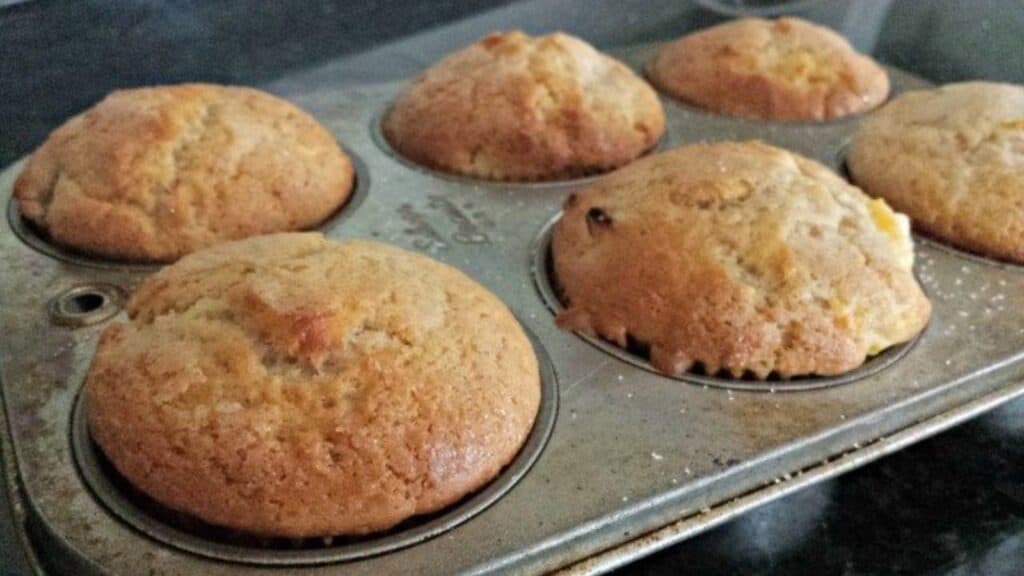 Peach kuchen muffins in a muffin tin.