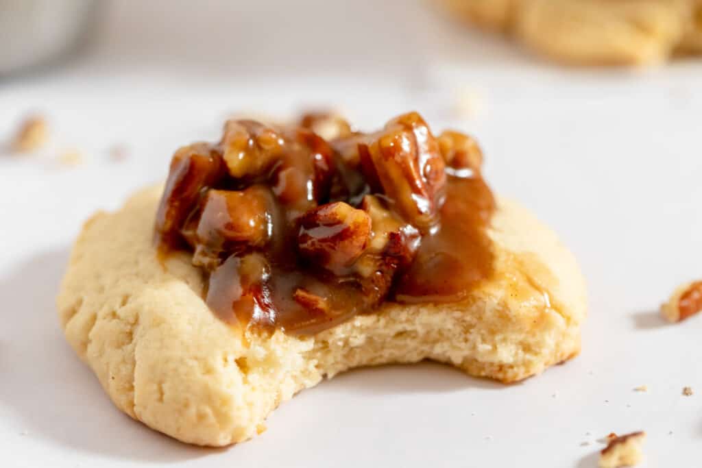 A pecan pie cookie on parchment paper with a bite taken out of it. 