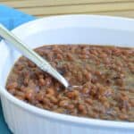 Pot of homemade baked beans on a wooden table.
