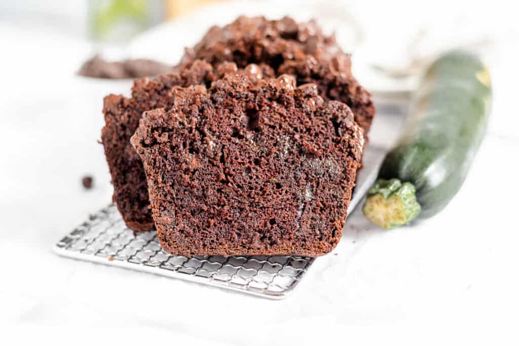 Chocolate Zucchini Bread on wire rack with zucchini beside it.