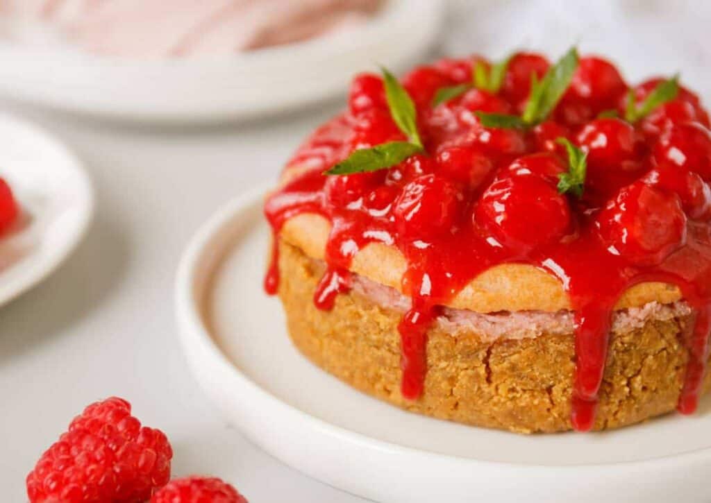 Lemon cheesecake with raspberry sauce on a plate.