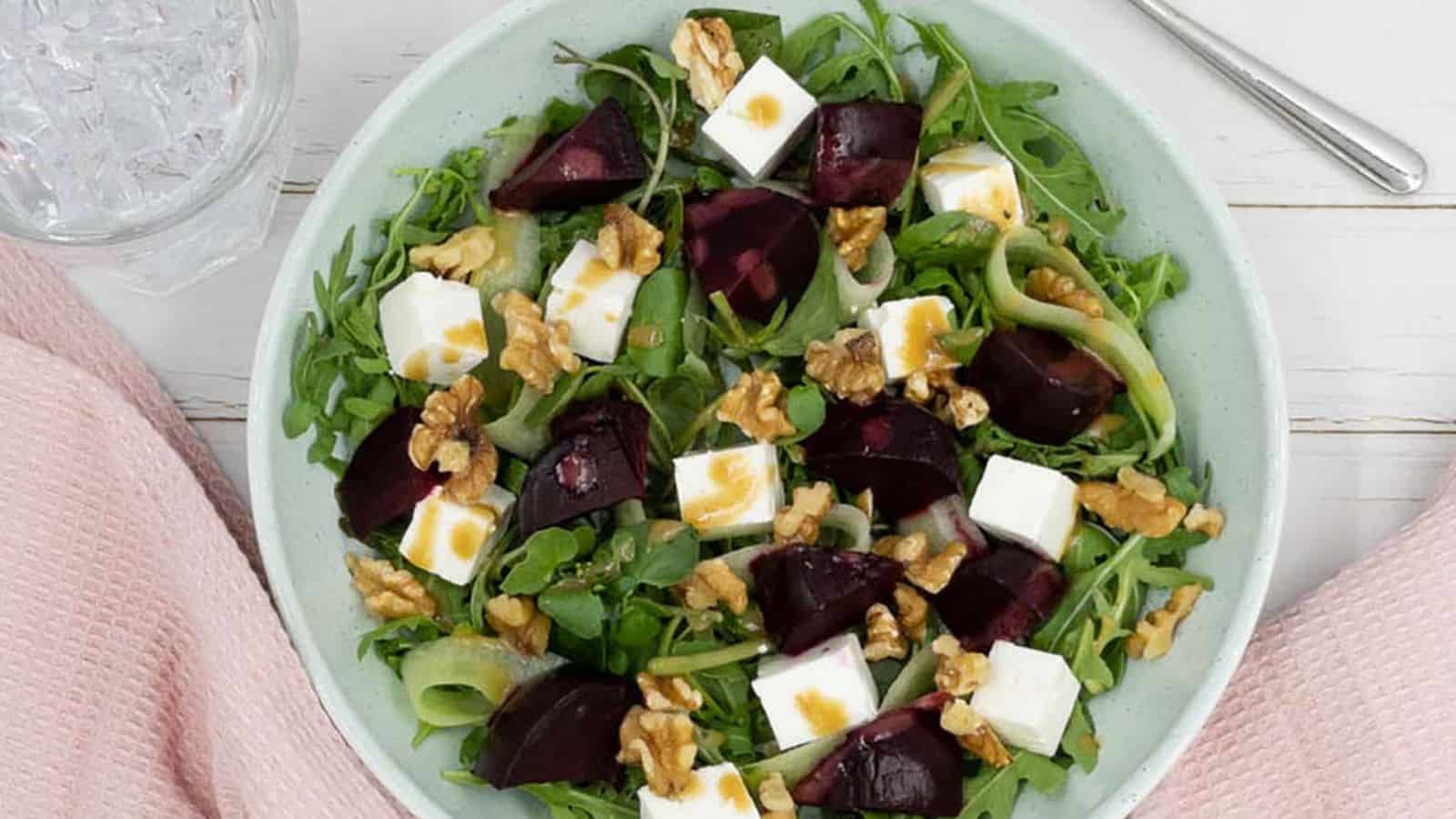 Roasted beetroot and feta salad in a bowl, with a light pink cloth around it.