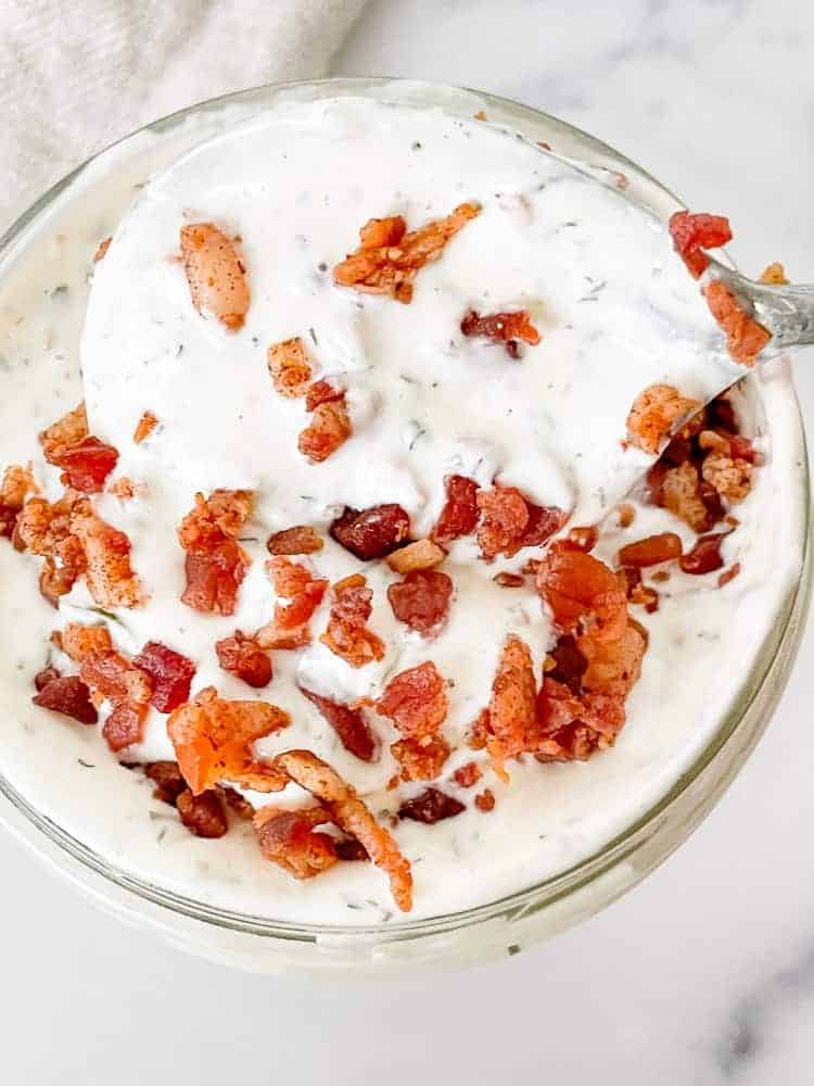A jar of Bacon Ranch Dressing with bacon on top of it.