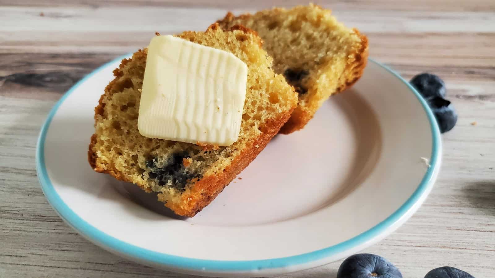 Sliced blueberry sour cream muffin with pat of butter.