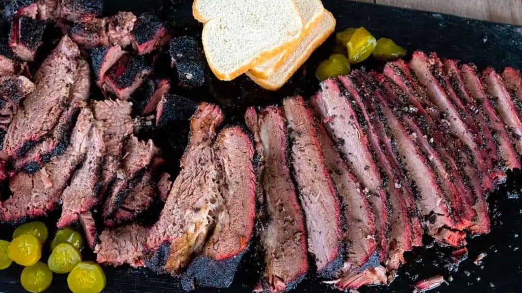 Platter of smoked brisket with bread and pickles.