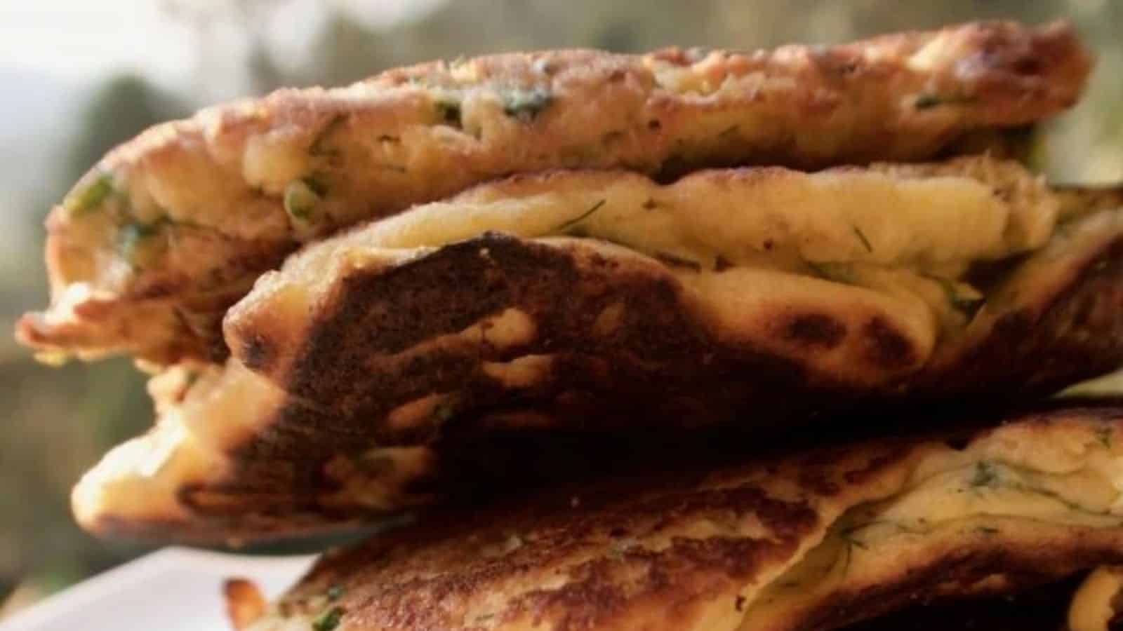 Savory Pancakes with Fennel and Feta in a stack on white plate.