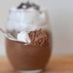 Image shows a Spoon with Baileys chocolate mousse and whipped cream and the full serving behind it.