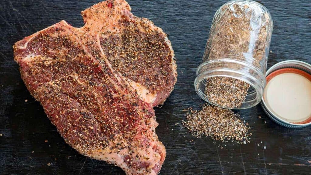 Steak rub spilled onto counter near porterhouse.