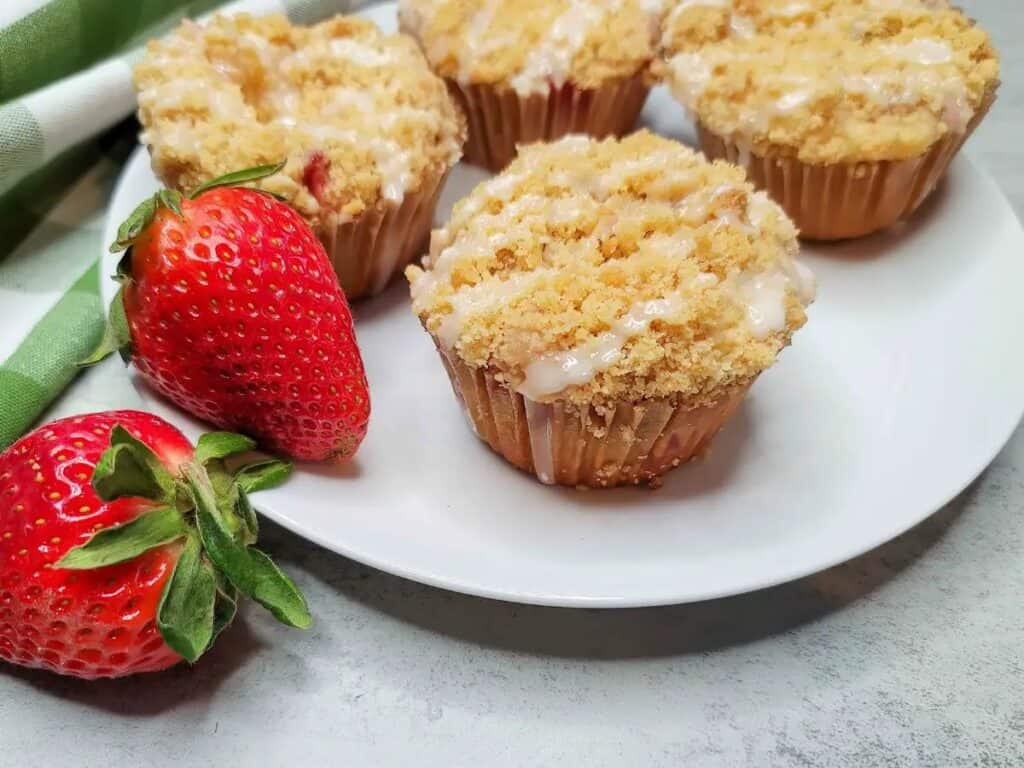 Strawberry muffins on a white plate with fresh strawberries