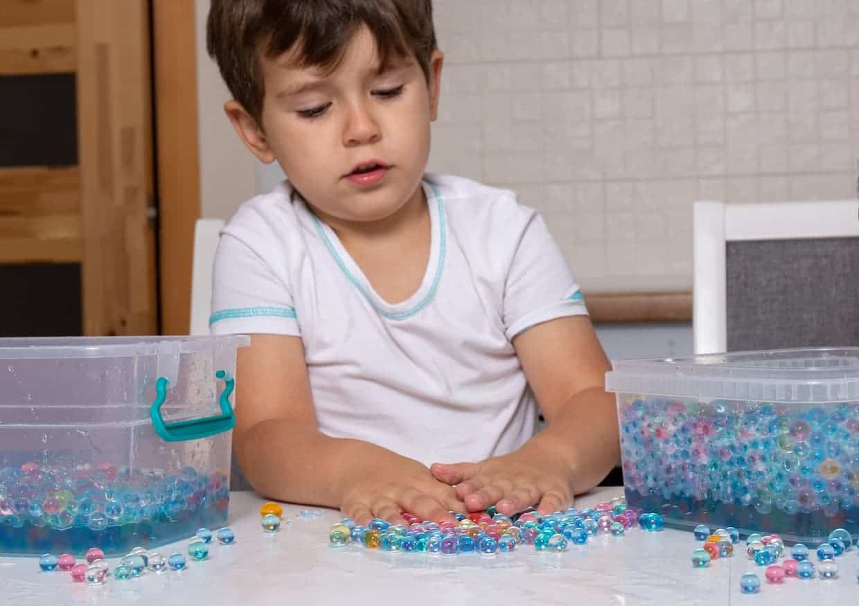 Toddler having sensory play with water beads.