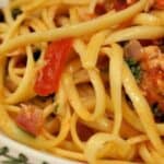 Image shows a closeup of tuna and tomato pasta in a shallow bowl.