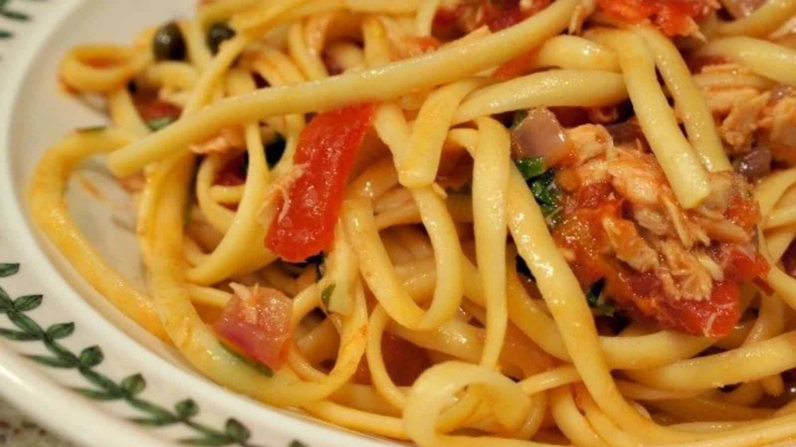 Image shows a closeup view of tuna and tomato pasta in a white patterned bowl.