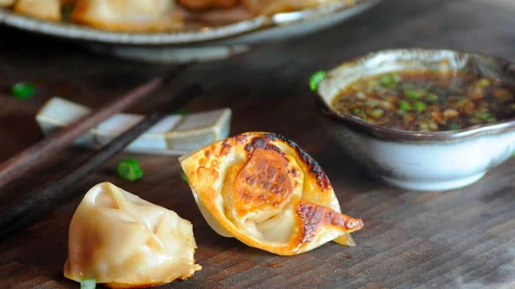 Potstickers on platter next to dipping sauce.