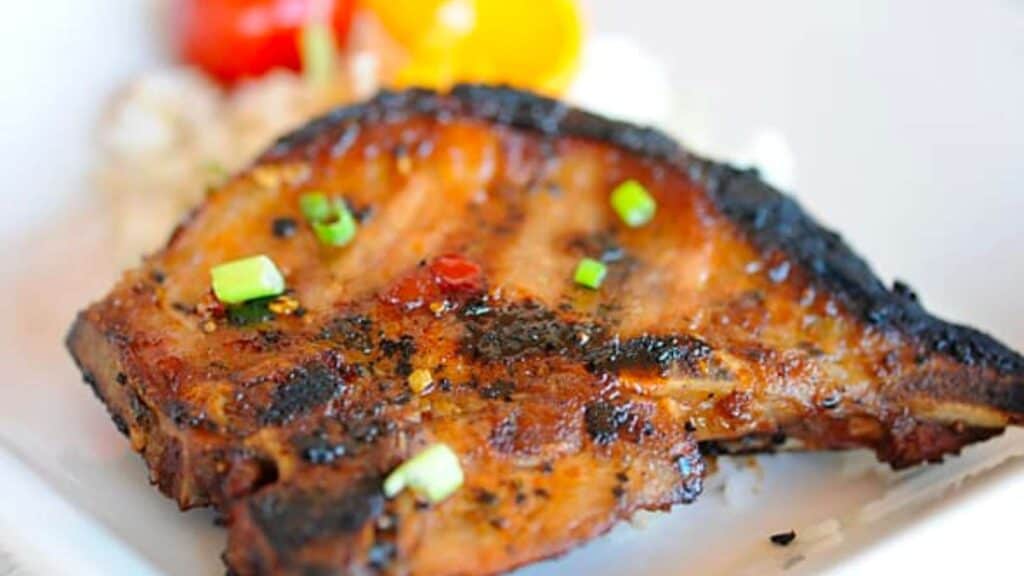 Grilled pork chop with orange sriracha glaze.