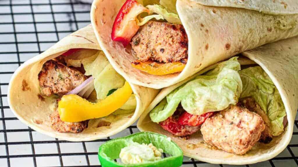 Three chicken tikka wraps with lettuce and peppers.