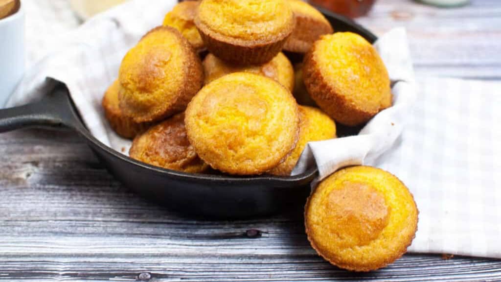 Pile of cornbread muffins on a white plate.