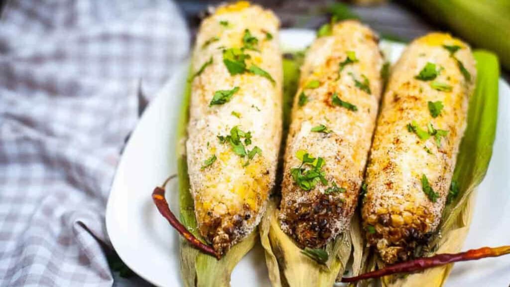 Corn elote on a white plate.