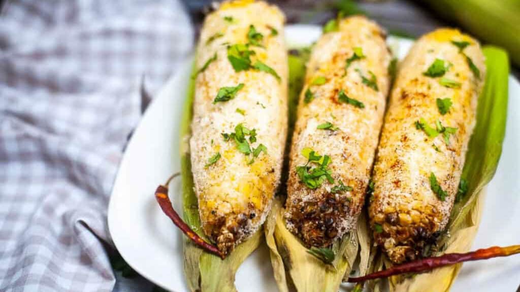 Corn elote on a white plate.