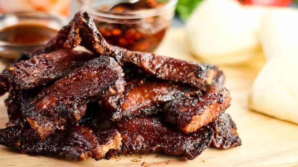 glazed pork belly on a wooden cutting board.