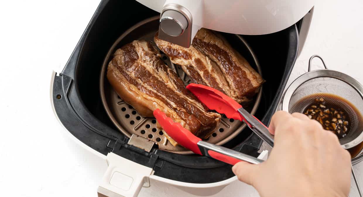 Flipping over steak in the air fryer using tongs.