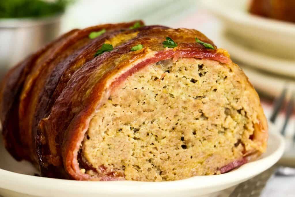 turkey meatloaf wrapped with bacon sliced on a plate.