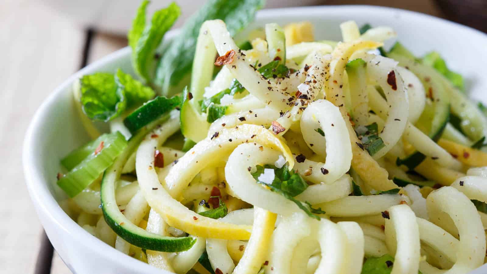 Basil mint squash noodles with freshly ground black pepper in a white bowl.