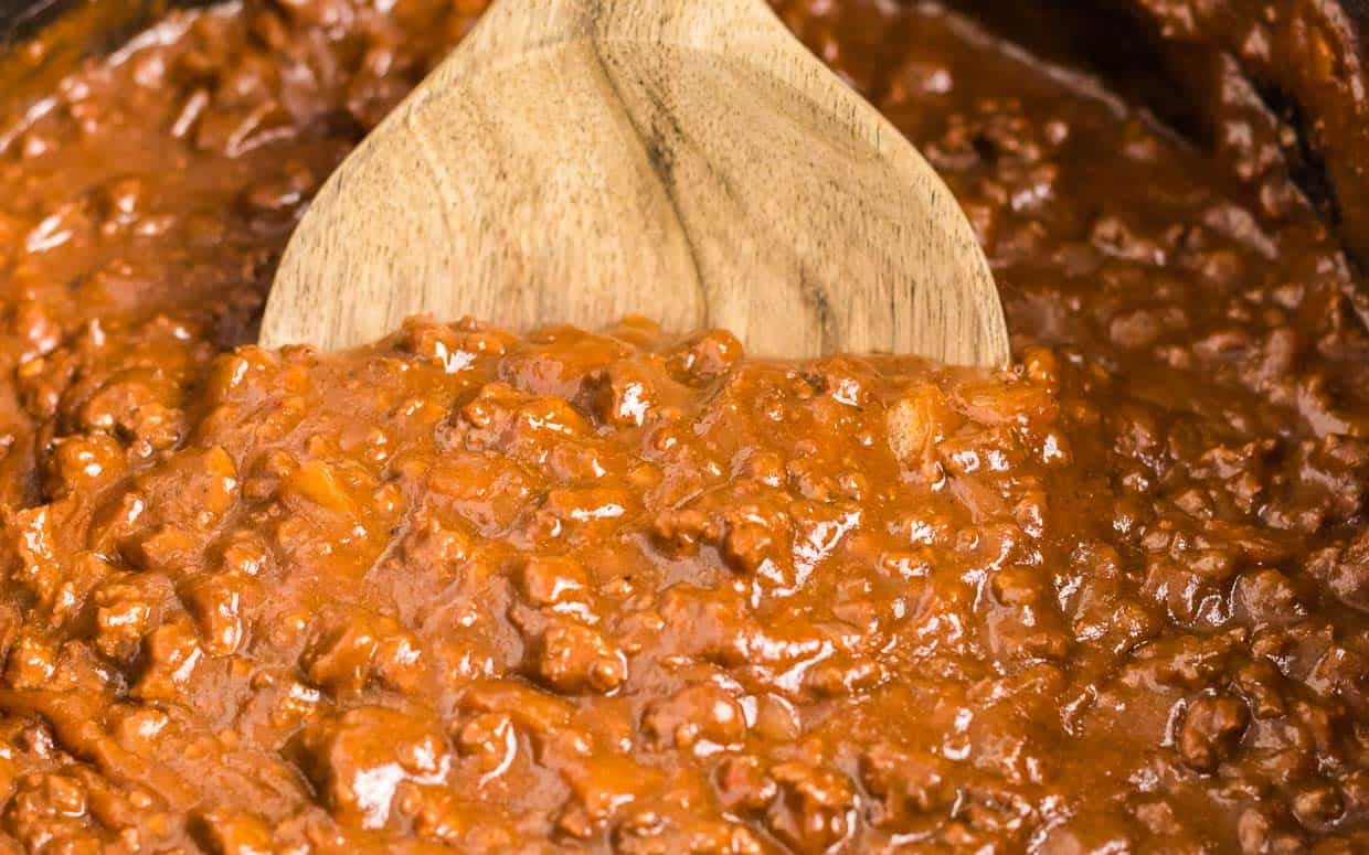 Chili in the crock pot with a wooden spoon.