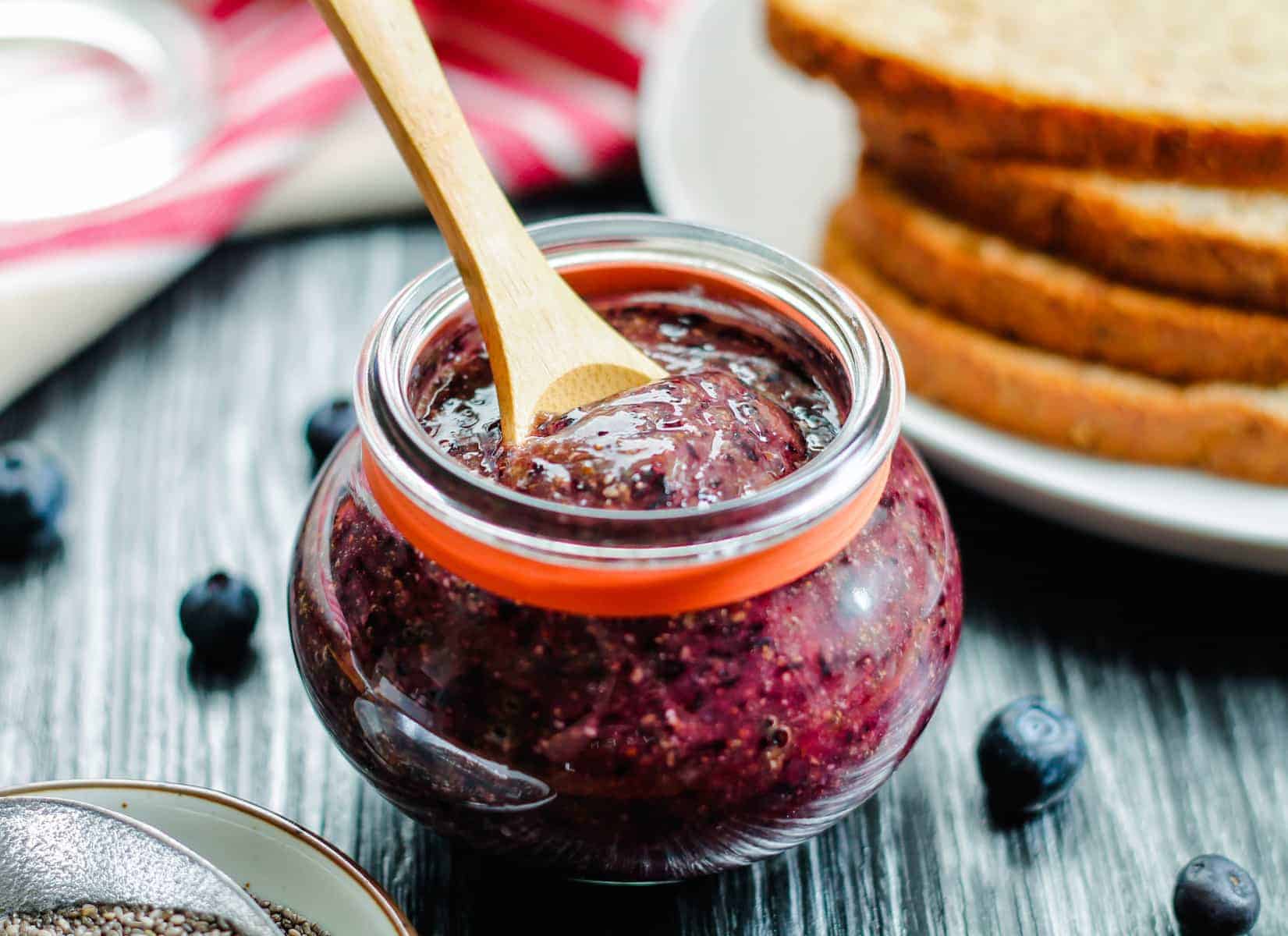 A jar of Blueberry Chia Jam with a spoon in it.