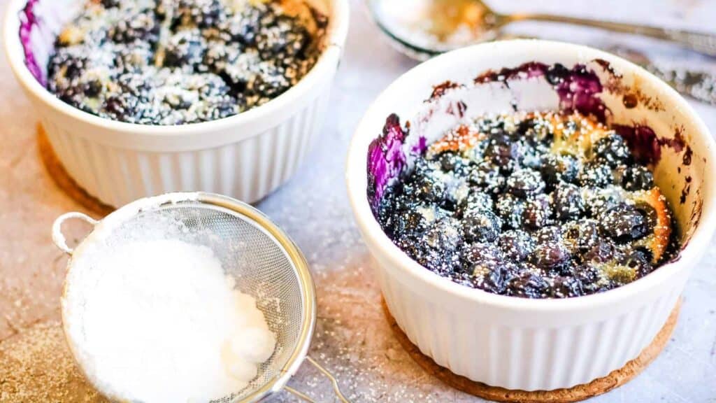 Blueberry clafoutis in ramekins with powdered sugar.