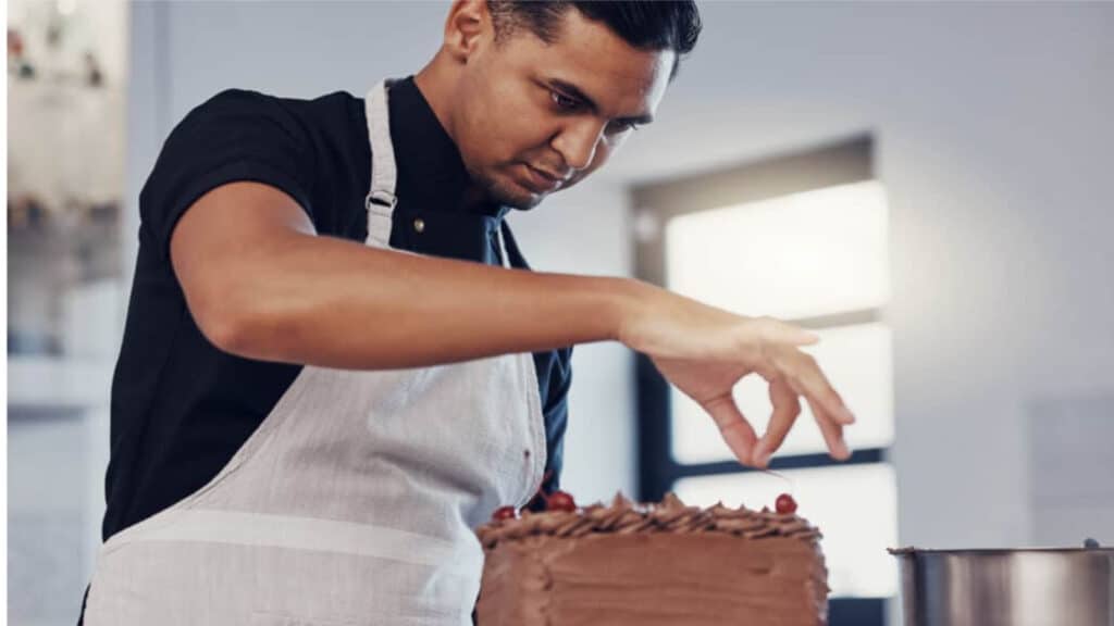 Man decorating a layer cake.
