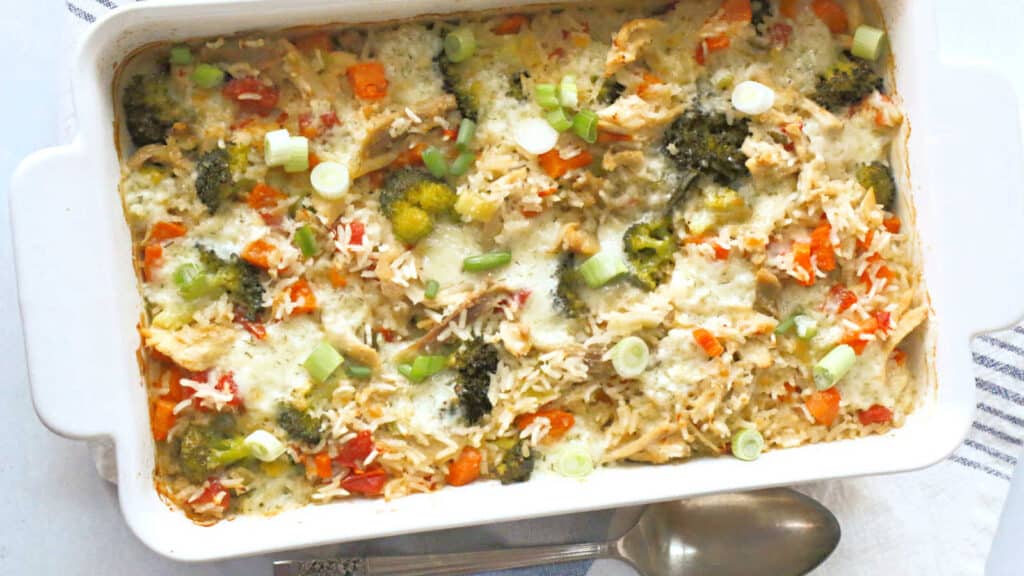 A chicken and rice casserole in a white baking dish on a white towel.
