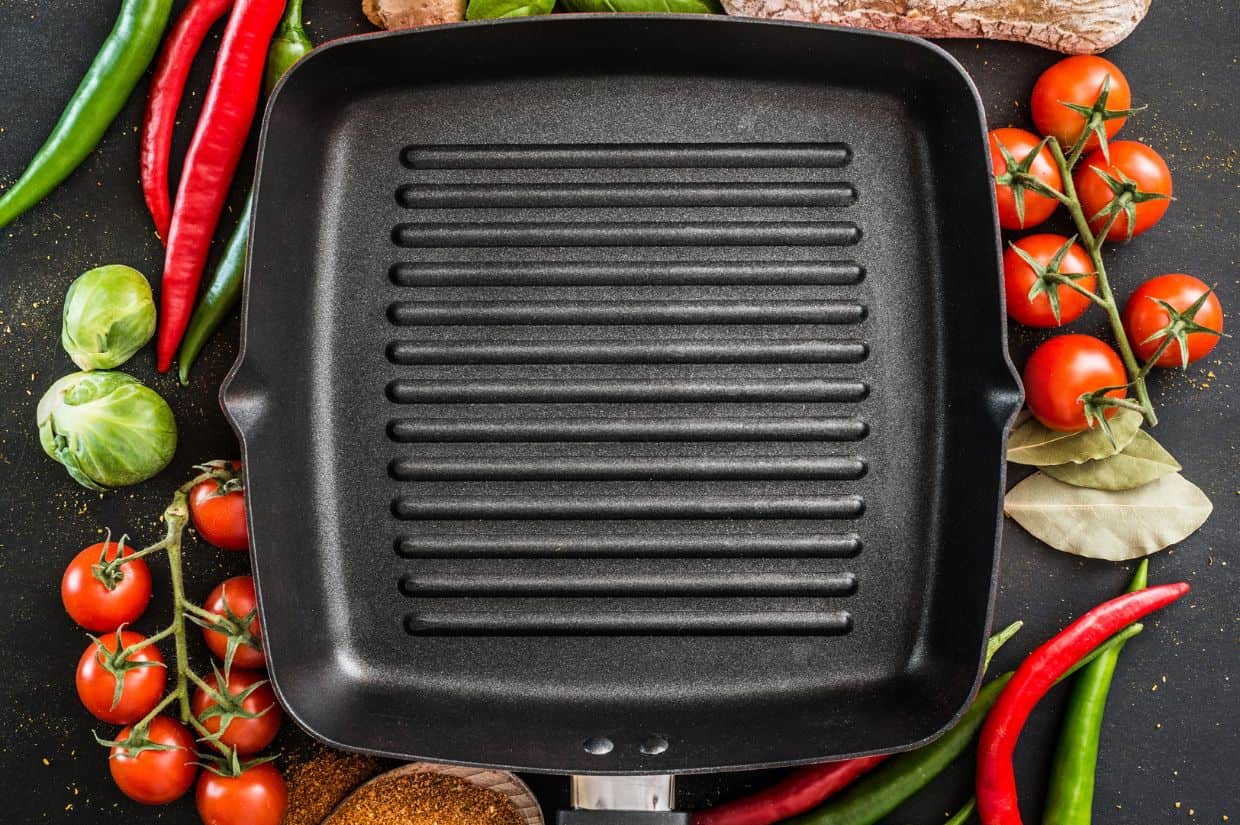 Cast iron grill pan with fresh ingredients surrounding. 
